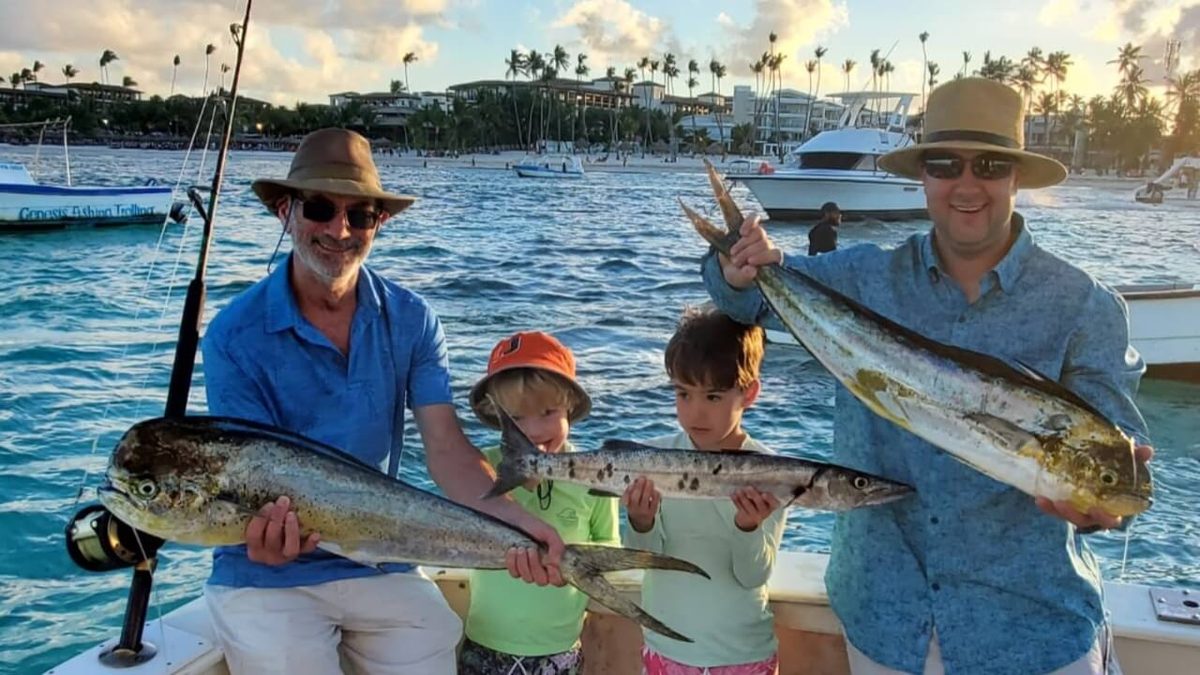 Family with kids holding their catch at sunset
